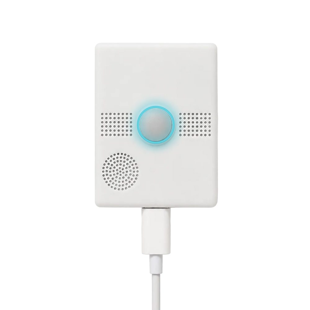 The white NxHUB device with its blue LED ring lit, round button, microphone grilles and speaker
